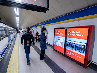 Varias personas frente a un cartel digital contra el presidente del Gobierno, en el metro de la Puerta del Sol, el 19 de mayo, en Madrid.