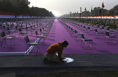 Un trabajador pega un cartel en una alfombra avisando del uso obligatorio de mascarilla como precaución contra el coronavirus en el lugar de las celebraciones del desfile del Día de la República en Nueva Delhi, India. La India celebra el Día de la República con un desfile militar y cultural reducido el 26 de enero.