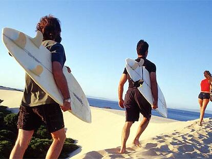 Las <b><i>webs</b></i> especializadas facilitan la búsqueda de apartamentos de alquiler para el verano, por ejemplo, cerca de las playas de Andalucía o Cataluña. En la foto, surfistas de camino a la Gran Duna, en Tarifa (Cádiz).