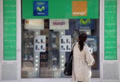 Mujer frente a una tienda de telefonía móvil.