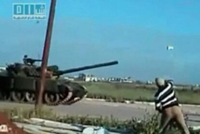 Un hombre lanza una piedra al paso de un tanque en la ciudad de Deraa.