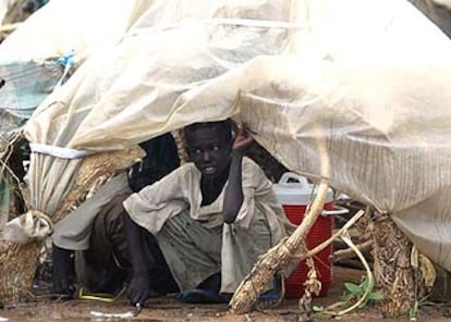 Un niño se refugia bajo un plástico para protegerse de la fuerte lluvia que caía en el campo de refugiados de Otash.