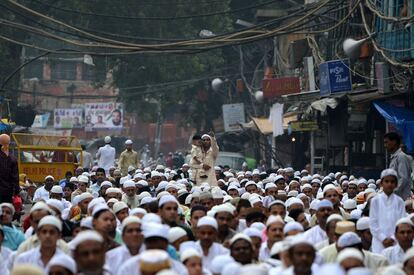 Un hombre lleva a su hijo en brazos durante la oración del fin de Ramadán, hoy, en Nueva Delhi.