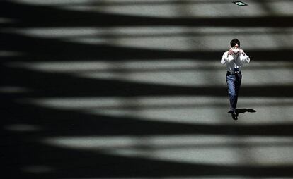 Un hombre camina por una solitaria calle de Tokio mientras se ajusta la mascarilla.