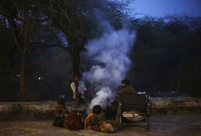 Personas sin hogar se calientan con una fogata en el borde de una carretera en Nueva Delhi (India).