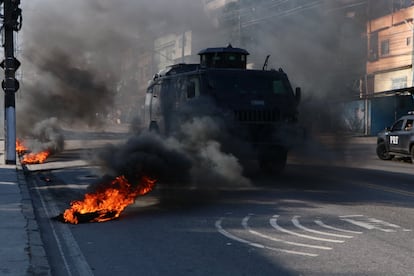Un vehículo policial detenido a mitad de la calle, rodeado por objetos en llamas, este 21 de julio en la favela Alemão, en Río de Janeiro (Brasil).