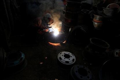 Hombre soldando llantas de neumáticos viejos para ser reutilizados en un taller en Rawalpindi, Pakistán.