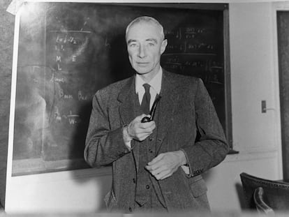 Robert Oppenheimer, standing before blackboard and holding pipe, in an undated photograph.