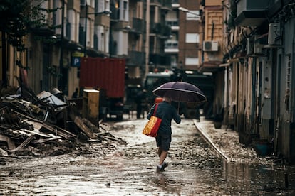 Un hombre se abre paso entre la lluvia y el barro en Paiporta, este domingo. 