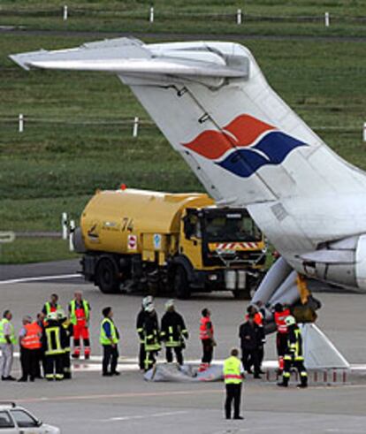 Los bomberos retiran el tobogán de emergencia del avión de Spanair.