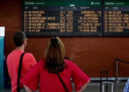 Dos viajeros observan las salidas de los trenes en la estación de Atocha, en Madrid.