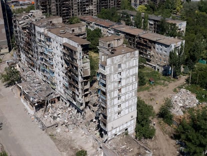 This aerial picture taken on July 13, 2022, shows destroyed buildings and residents in the yard in the city of Mariupol, amid the ongoing Russian military action in Ukraine. (Photo by Andrey BORODULIN / AFP)