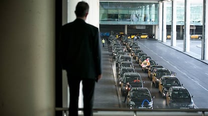 Usuarios del aeropuerto de Barcelona observan la marcha de taxistas en huelga.