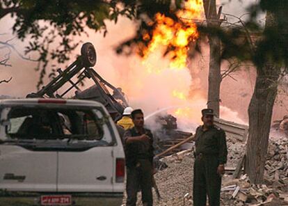 Dos policías afganos en el lugar donde explotó ayer un coche bomba en Kabul.