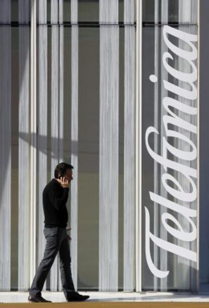 Un hombre camina junto a la torre de Telefónica en Barcelona