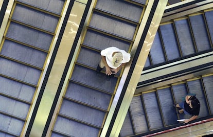 Un hombre y una mujer caminan por las escaleras mecánicas de un centro comercial en Yakarta (Indonesia).