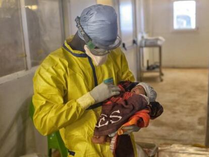 Un trabajador de MSF sostiene en sus brazos a Nubia en el centro de tratamiento de ébola de Conakry.