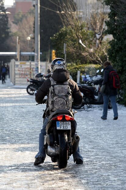 Un joven intenta aparcar su moto, con bastante dificultad por las placas de hielo, en  la Diagonal de Barcelona.