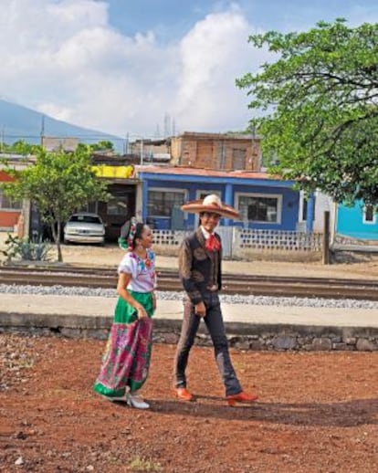 Una mujer con traje tradicional y un hombre vestido de mariachi pasean por Tequila (Jalisco).