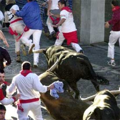 Varios toros de la ganadería sevillana de Juan Pedro Domecq resbalan en la curva de acceso a Estafeta durante el octavo y último de los encierros de los Sanfermines 2004.
