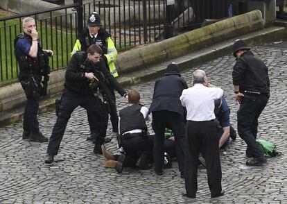 Policiais apontam para um homem caído no chão após o incidente no Parlamento, em Londres.