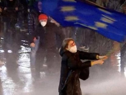 La manifestante Nana Malashkhi enarbola la bandera de la Unión Europea frente a un cañón de agua de la policía antidisturbios, en Georgia.