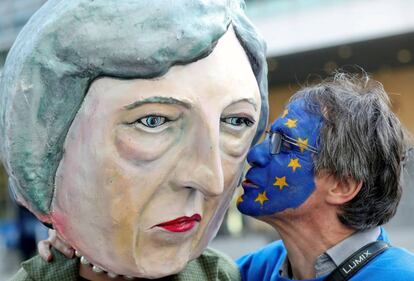 Un manifestante en contra del Brexit le da un beso a una máscara de Theresa May.
