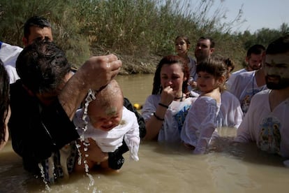 Un sacerdote serbo-ortodoxo bautiza a un bebé en el Jordán el abril.