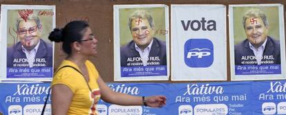 Una vecina pasa por delante de los carteles electorales de Alfonso Rus colocados en la noche del jueves en X&agrave;tiva.