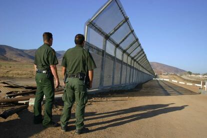 Dos policías vigilan la frontera de México con Estados Unidos.