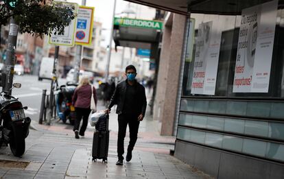 Un hombre camina con una maleta en Madrid. Luis Sevillano / EL PAÍS