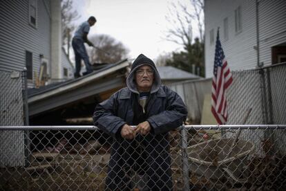 Paul Hernández posa en la valla de su casa de New Dorp, Staten Island, mientras un obrero arregla un tejado. Hernández y otros vecinos se quejan de los pocos esfuerzos realizados por las autoridades del estado de Nueva York para proteger la localidad de las inundaciones durante el huracán Sandy.