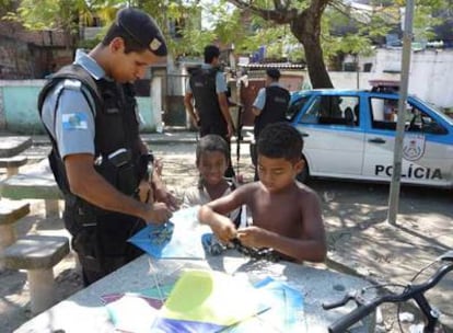 Un policía pacificador ayuda a dos niños a montar una cometa en la favela Ciudad de Dios de Río de Janeiro.