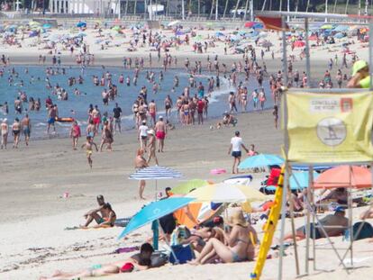 Personas disfrutan del sol y las altas temperaturas este domingo, día de las elecciones gallegas, en la playa de La Fuente en Vigo, Pontevedra.