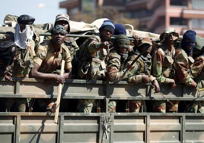 Los miembros del ejército hacen un gesto al fotógrafo mientras patrullan las calles de la capital, en Harare.