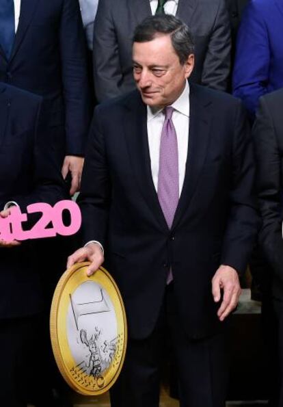 Mario Draghi, presidente del Banco Central Europeo, muestra una reproducción del euro. 