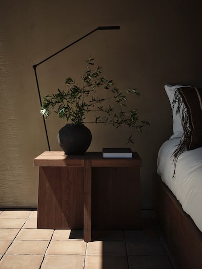 Dos piezas de Van Duysen, en una habitación de Portugal: una mesa de madera (para él, las mesas auxiliares son muebles versátiles que pueden actuar en distintas estancias y tener diferentes utilidades) y un jarrón negro.