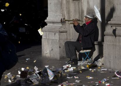 Un músico callejero toca la trompeta, en la Gran Vía, rodeado de basura, 15 de noviembre de 2013.