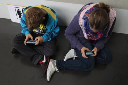 Dos niños ensimismados con sus móviles.
