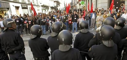 Un grupo de personas que secundan la huelga general grita frente a unos agentes de policía en la cercanía de un centro comercial de la calle Preciados, de Madrid.