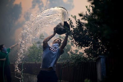 Un hombre lanza un cubo de agua para apagar el incendio forestal en Oliveira De Azemeis, Portugal, este lunes.
