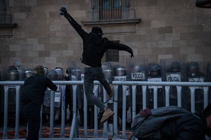 Un manifestante golpea una valla detrás de la cuál se resguardan policías antidisturbios, en las calles del Centro Histórico de la capital.