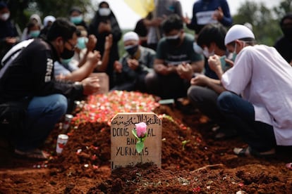 Varios familiares rezan después del funeral de un padre que murió por complicaciones de la covid en un cementerio en Depok, Indonesia.