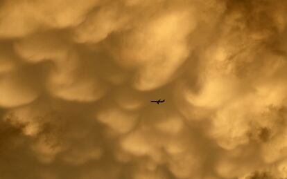 Un avión en vuelo bajo un manto de nubes doradas teñidas por la luz del sol en el cielo de Chicago.