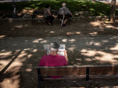 Una persona mayor leyendo un periodico en el parque Caramuel, en el barrio de Madrid.