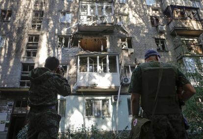 Dos separatistas prorrusos observan el eficio dañado por el ejército ucraniano en Donestk.