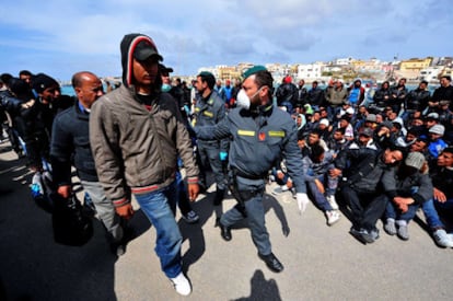 Policías escoltan a inmigrantes tunecinos hoy en Lampedusa