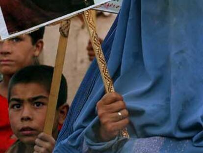 Una mujer con <i>burka</i> porta la foto de la candidata Suraia Perlilka.