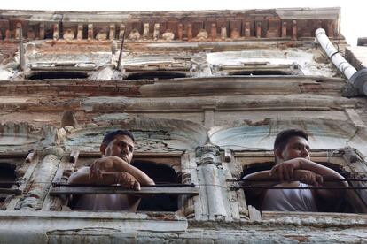 Vecinos miran por la ventana después de que el techo de una casa cercana se ha derrumbado en Amritsar, India.