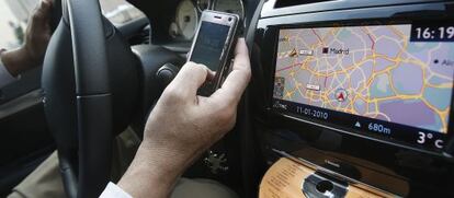 Un conductor mira su tel&eacute;fono m&oacute;vil, utiliza el GPS y pone un CD en su veh&iacute;culo. 
  
  
 